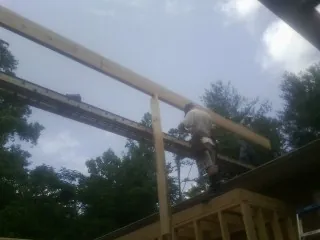 Carpenter setting a ridge beam over a new addition frame — Ice Dam Removal by Roofing Brothers in Lathrop