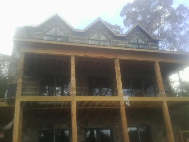 Dormers and porch framing on a large log home under construction — Roof Coating work by our crew in Lathrop