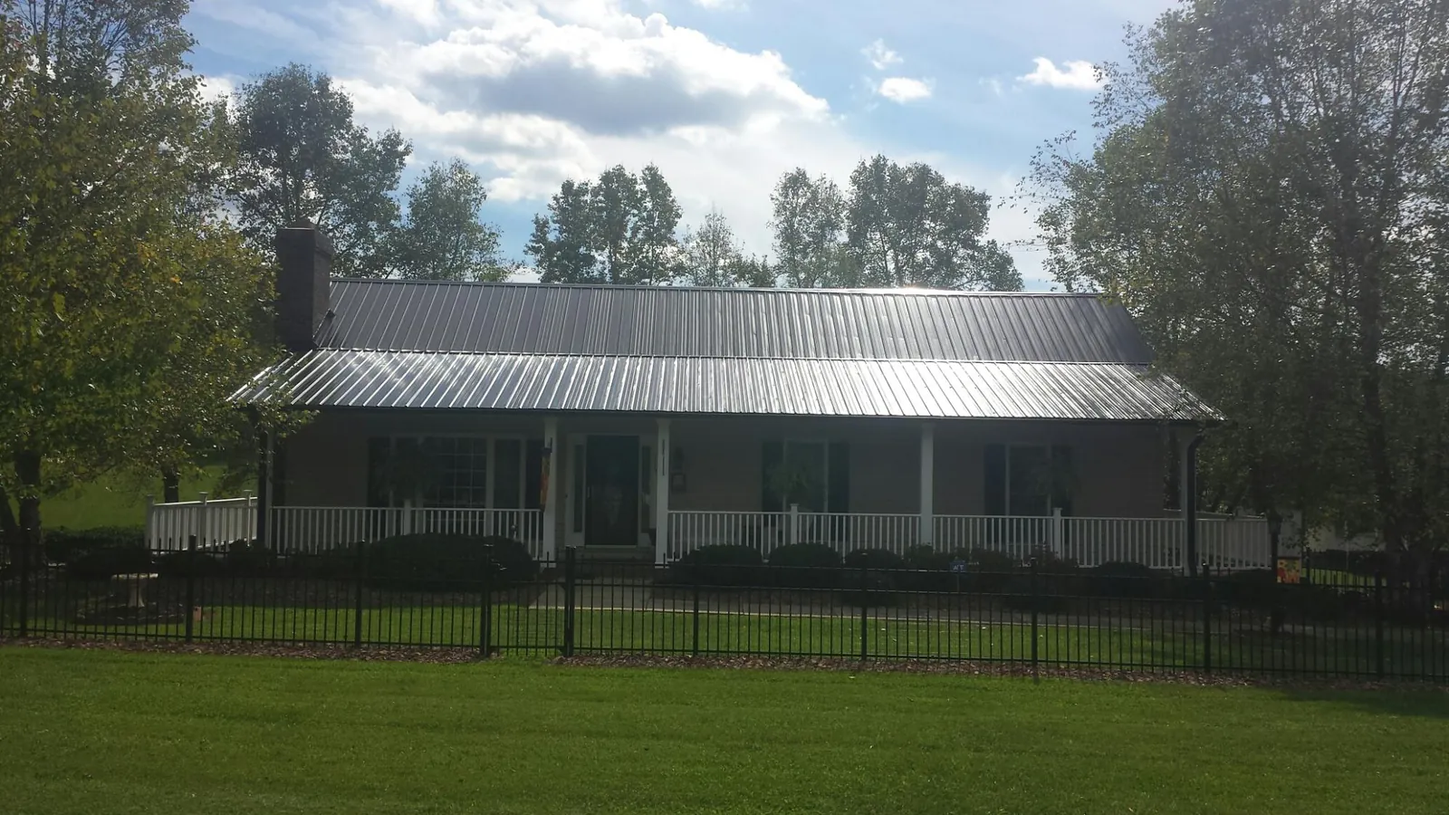 Gray metal roof on a brick ranch with a full width front porch — Gutter Guard Installation work by our crew in Lathrop
